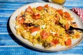 Plate with homemade chicken salad, carrot, tomato and brown rice on a rustic blue wooden table. heatly food