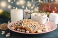 Plate of homemade Christmas cookies, marshmallows on wooden table, against blue background, space for text. Closeup Royalty Free Stock Photo