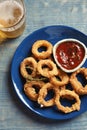 Plate with homemade crunchy fried onion rings and tomato sauce on wooden background Royalty Free Stock Photo