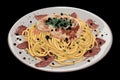 plate with hot pasta, bacon, meat and black pepper