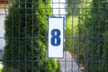 Plate with house number eight hanging on iron fence outdoors Royalty Free Stock Photo