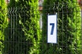 Plate with house number 7 hanging on iron fence outdoors