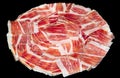 Plate of Iberian pork ham on black background