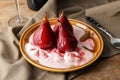 Plate with ice cream and sweet pears stewed in red wine on wooden table