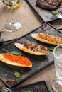 Plate of Italian appetizer bruschetta with different smoked fish and glass of white wine on table at restaurant Royalty Free Stock Photo