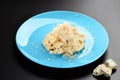 Plate of Italian Penne pasta with a formaggio creamy savory sauce and basil served in a blue dish black menu Royalty Free Stock Photo