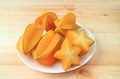 Plate of Juicy Fresh Ripe Starfruit`s Cross Sections with Whole Fruit on the Wooden Table