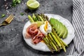 Plate with a keto diet food. baked asparagus with poached Egg, avocado and prosciutto, jamon, bacon. Keto breakfast Royalty Free Stock Photo