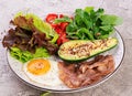 Plate with a keto diet food. Fried egg, bacon, avocado, arugula and strawberries. Royalty Free Stock Photo