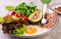 Plate with a keto diet food. Fried egg, bacon, avocado, arugula and strawberries. Royalty Free Stock Photo