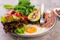 Plate with a keto diet food. Fried egg, bacon, avocado, arugula and strawberries. Royalty Free Stock Photo