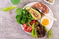 Plate with a keto diet food. Fried egg, bacon, avocado, arugula and strawberries. Royalty Free Stock Photo