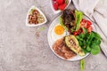 Plate with a keto diet food. Fried egg, bacon, avocado, arugula and strawberries.