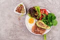 Plate with a keto diet food. Fried egg, bacon, avocado, arugula and strawberries. Royalty Free Stock Photo