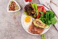 Plate with a keto diet food. Fried egg, bacon, avocado, arugula and strawberries. Royalty Free Stock Photo