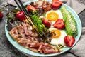 Plate with a keto diet food. fried egg, bacon, avocado, strawberries and fresh salad. Keto breakfast. place for text, top view Royalty Free Stock Photo