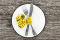 plate with a knife and fork wrapped in measuring tape on a wooden background. diet concept Royalty Free Stock Photo