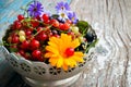 A plate of leaves and berries of black and red currant with a flower on a wooden Royalty Free Stock Photo