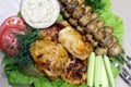 In a plate lies fried chicken thighs, mushrooms on skewers with vegetables Royalty Free Stock Photo