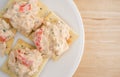 Plate of lobster dip on saltine crackers atop wood table