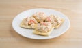 Plate of lobster dip on saltine crackers on a wood table