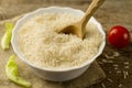 Plate of long grain rice with a spoon, cherry tomato, green lettuce on wooden background