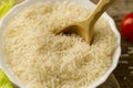 plate of long grain rice with a spoon, cherry tomato, green lettuce on wooden background