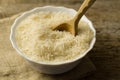 Plate of long grain rice with spoon on wooden background