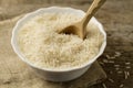 Plate of long grain rice with spoon on wooden background