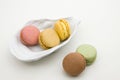 Plate with macarons of different flavors on white background