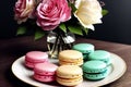 A plate of macarons and roses on a table.