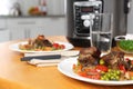 Plate with meat and garnish prepared in multi cooker on wooden table in kitchen. Space for