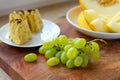 A plate of melon slices, homemade cake, green grapes on a wooden background, concept of fresh fruits and healthy food Royalty Free Stock Photo