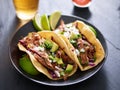 Plate of mexican carnita tacos with beer in background Royalty Free Stock Photo