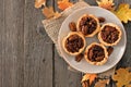 Plate of pecan pie tarts, overhead table scene on wood Royalty Free Stock Photo