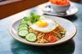 plate of nasi goreng with fried egg on top, garnished with cucumber slices