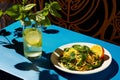 a plate of noodles and a glass of lemonade on a blue table