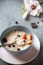 Plate of oatmeal with berries and pieces of pear and chocolate on a gray background, a Magnolia flower, Breakfast