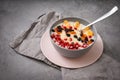 1 plate of oatmeal porridge with fruit slices, tangerine slices, raisins, dried apricots, pomegranate seeds on a gray