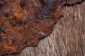 Plate of old rotten rusted metal lying on a wooden board. Iron rust and aged wood texture background. Macro shot of Royalty Free Stock Photo