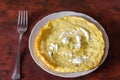 A plate of omelet, herbs and sour cream on the red kitchen table