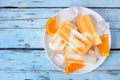 Plate of orange yogurt popsicles over rustic blue wood