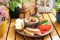 Plate with humus in a bowl decorated with pomegranate seeds, vegetable snacks, bread, on a wood table, selective focus.