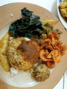 A plate of padang rice with prawn, potato cake and cassava leaves. Image print for illustration and food article.