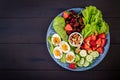 Plate with a paleo diet food. Boiled eggs, avocado, cucumber, nuts, cherry and strawberries. Royalty Free Stock Photo