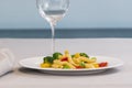 A plate of pasta salad with an out of focus glass at the back Royalty Free Stock Photo