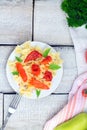 Plate of pasta with tomato sauce with ingredients for cooking on white wooden background, top view with copy space