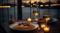 A plate of pasta and wine on a table with a view of the water and a bridge in the background with candles and a glass of wine.