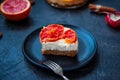 Plate with piece of baked cheesecake with red grapefruit slices and vintage fork on the black stone background with ingredients. S Royalty Free Stock Photo