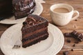 Plate with piece of delicious chocolate cake and cup of coffee on wooden table Royalty Free Stock Photo